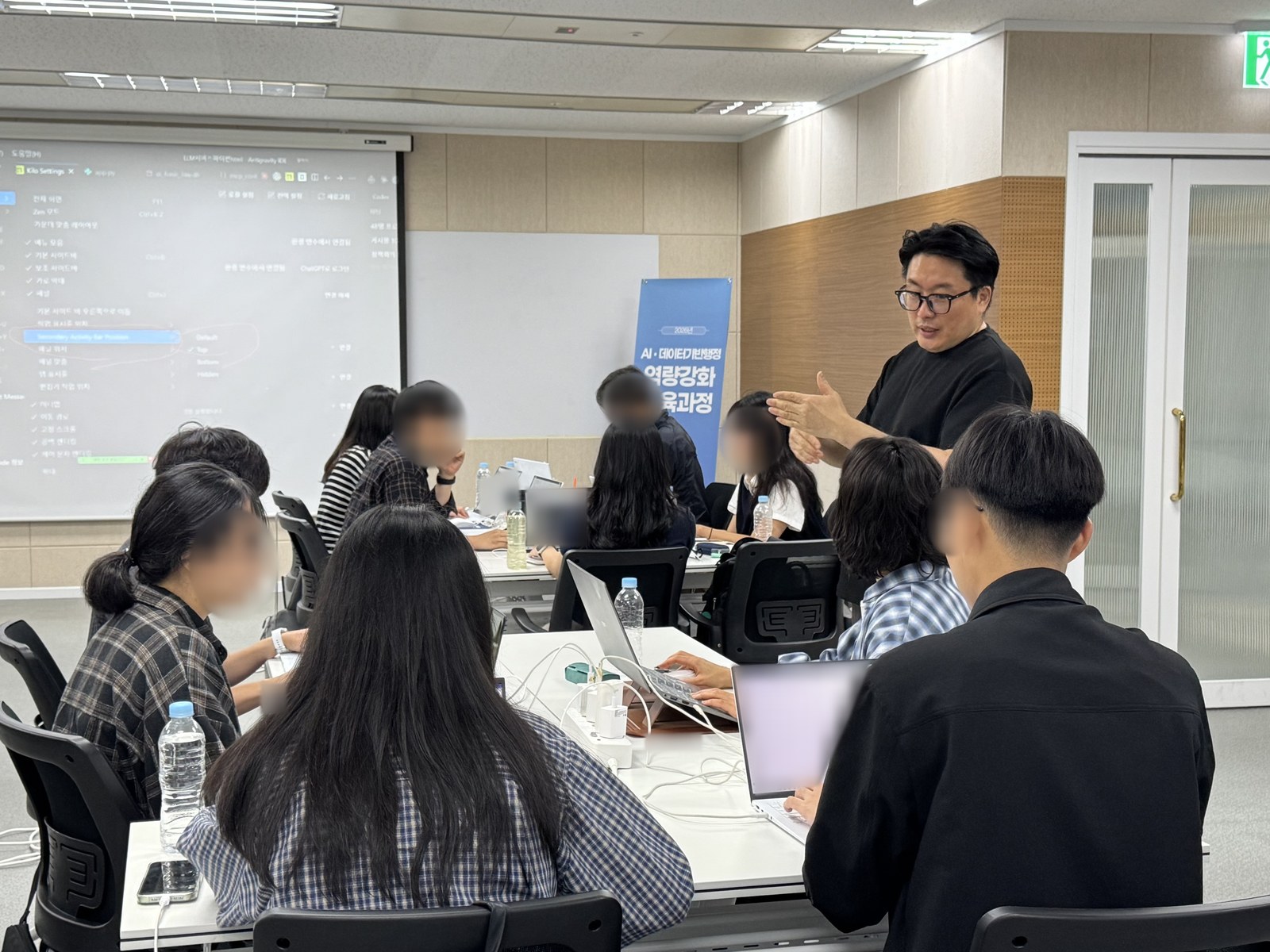 배너 앞에서 강사가 설명하고, 수강생들은 각자 노트북으로 실습을 따라갑니다.