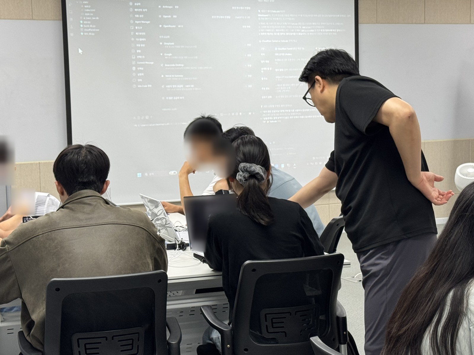 강사가 수강생 자리로 가서 노트북 화면을 함께 보며 설명합니다.